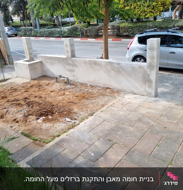 אזור חפור עם אדמה, קיר בטון חדש, שקי חומרי בניין